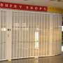 Sliding security shutter with a custom curve, securing an airport duty-free shop.