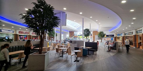Interior of the Baldock motorway services area with shops situated around a wide indoor oval seating area