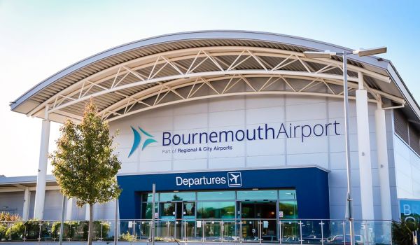 Entrance of the Bournemouth Airport terminal building under a bright blue sky