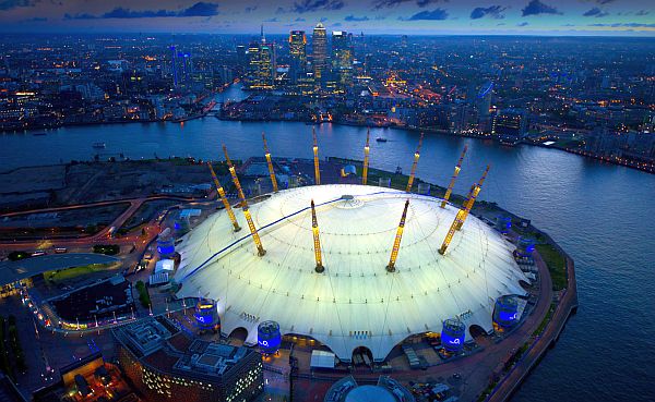 Birds-eye view of the O2 Arena with the river Thames going around and the skyline of the city of London in the background in fading evening light