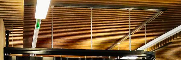 detail of the support system for the sliding shutter at Bristol University, showing the shutter's top-track hanging from supports, connected to unistrut channel fixed to the timber slats on the ceiling